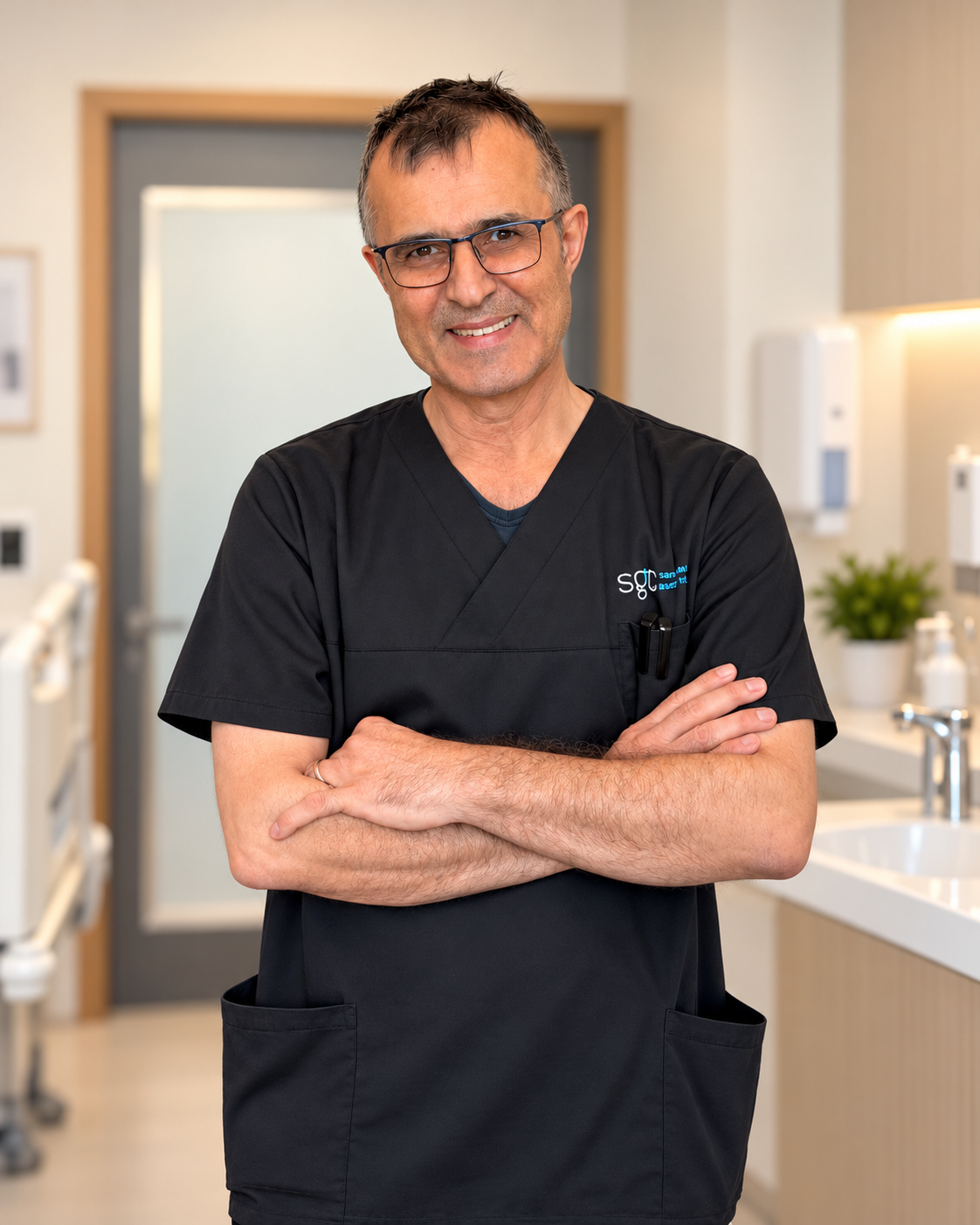 Porträtt av en mörkhårig man med glasögon i klinikens arbetskläder